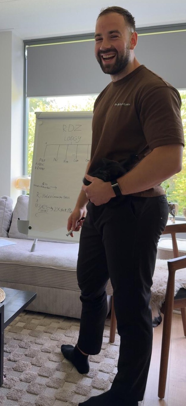 Isaak lachend tijdens een sessie, met het whiteboard op de achtergrond